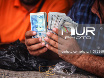 A man is counting stacks of Israeli shekel banknotes at an informal money exchange stall in Deir el-Balah in the central Gaza Strip on July...