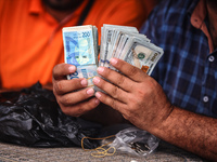 A man is counting stacks of Israeli shekel banknotes at an informal money exchange stall in Deir el-Balah in the central Gaza Strip on July...