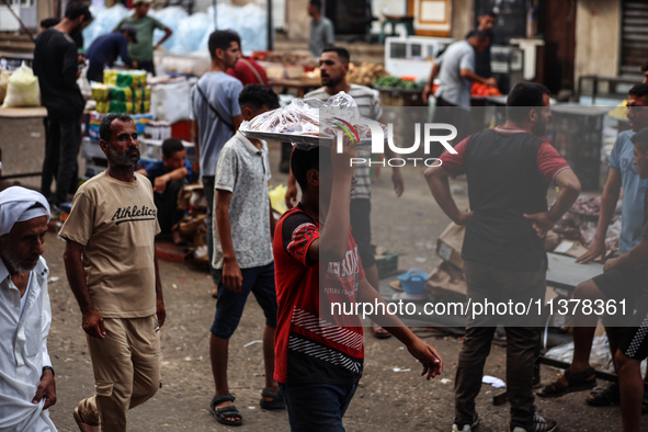 People are walking along a crowded market street in Deir el-Balah in the central Gaza Strip on July 2, 2024, amid the ongoing conflict in th...