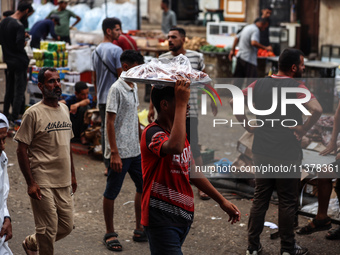 People are walking along a crowded market street in Deir el-Balah in the central Gaza Strip on July 2, 2024, amid the ongoing conflict in th...