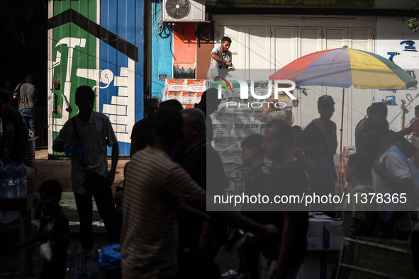 People are walking along a crowded market street in Deir el-Balah in the central Gaza Strip on July 2, 2024, amid the ongoing conflict in th...