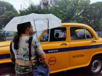 A woman is holding an umbrella, standing on the street, and waiting for buses during the rainy season in Kolkata, India, on July 2, 2024. (