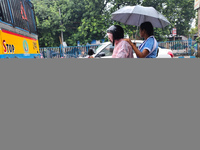 People are riding on a scooter in rainy weather in Kolkata, India, on July 2, 2024. (