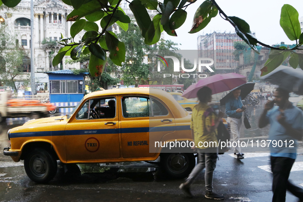 People are holding umbrellas and walking on a busy road in the monsoon rain in Kolkata, India, on July 2, 2024. 