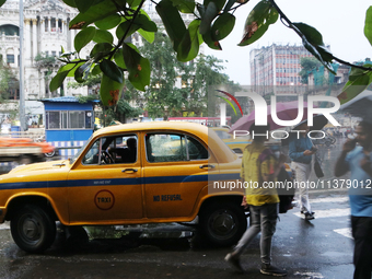 People are holding umbrellas and walking on a busy road in the monsoon rain in Kolkata, India, on July 2, 2024. (