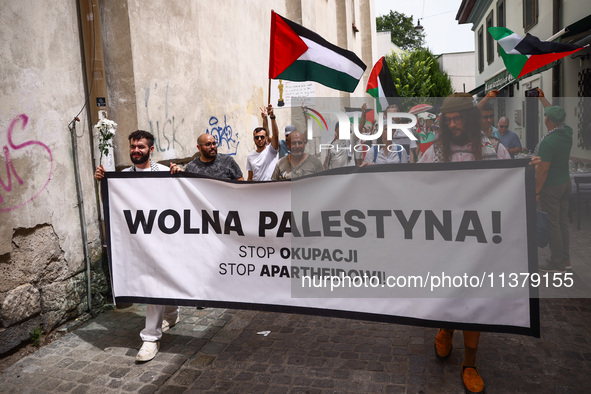 People hold  'Free Palestine'  banner attending solidarity with Palestine demonstration at Kazimierz, the Jewish historic district in Krakow...