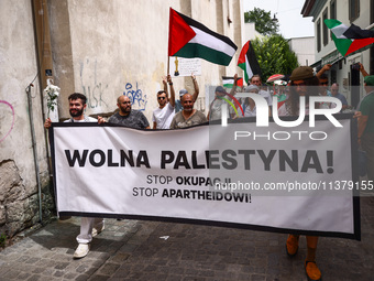 People hold  'Free Palestine'  banner attending solidarity with Palestine demonstration at Kazimierz, the Jewish historic district in Krakow...