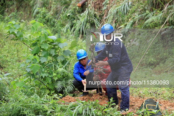 Electric power repair personnel are fixing the ground anchor of a pole in Si'an village, Rongan County, Liuzhou city, South China's Guangxi...