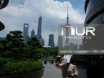 A woman is using an envelope to block the sun during the heatwave in Shanghai, China, on July 3, 2024. (