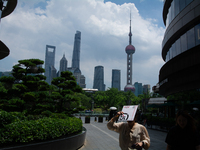 A woman is using an envelope to block the sun during the heatwave in Shanghai, China, on July 3, 2024. (