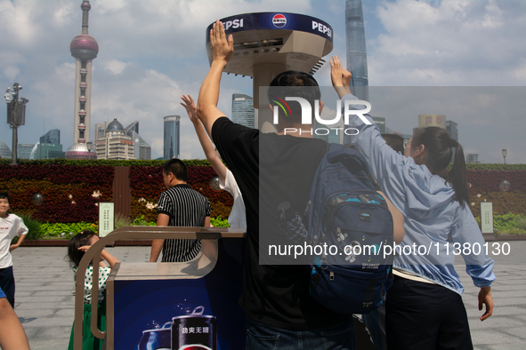 People are trying to reach the mist sprinkler during the heatwave at the Bund in Shanghai, China, on July 3, 2024. 