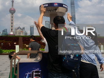 People are trying to reach the mist sprinkler during the heatwave at the Bund in Shanghai, China, on July 3, 2024. (