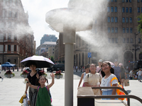 People are trying to reach the mist sprinkler during the heatwave at the Bund in Shanghai, China, on July 3, 2024. (