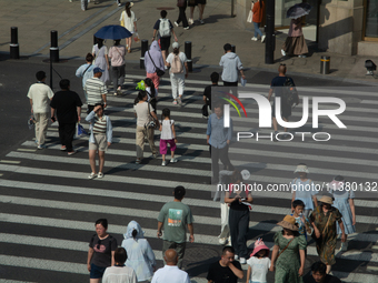 People are walking across the street during the heatwave on Nanjing Road in Shanghai, China, on July 3, 2024. (