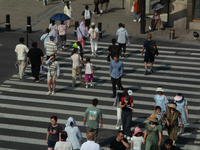 People are walking across the street during the heatwave on Nanjing Road in Shanghai, China, on July 3, 2024. (