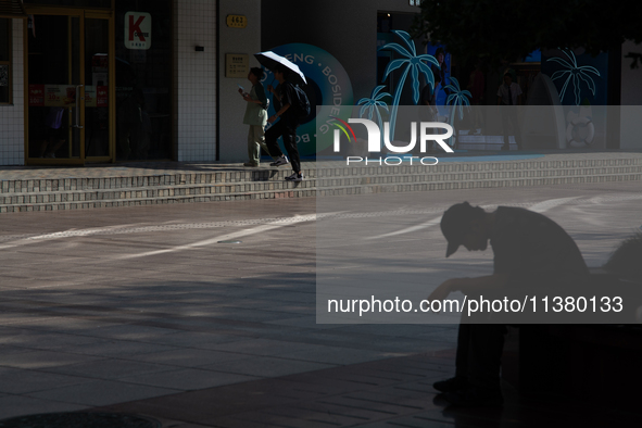 A man is resting on the bench during the heatwave on Nanjing Road in Shanghai, China, on July 3, 2024. 