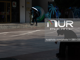 A man is resting on the bench during the heatwave on Nanjing Road in Shanghai, China, on July 3, 2024. (