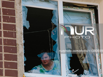 A woman is standing in a window broken by an airstrike, in Kharkiv, Ukraine, on July 3, 2024. On the afternoon of July 3, 2024, Russia launc...