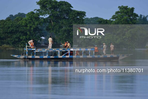 An Indian forest guard is patrolling floodwaters on a boat inside the Pobitora Wildlife Sanctuary in Morigaon District of Assam, on July 3,...