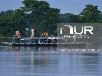 An Indian forest guard is patrolling floodwaters on a boat inside the Pobitora Wildlife Sanctuary in Morigaon District of Assam, on July 3,...