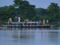 An Indian forest guard is patrolling floodwaters on a boat inside the Pobitora Wildlife Sanctuary in Morigaon District of Assam, on July 3,...