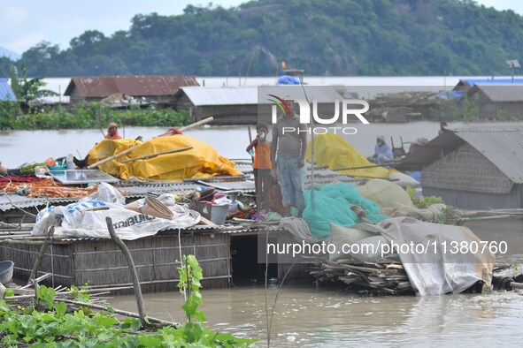 Villagers are taking shelter on the top of their partially submerged hut in a flood-affected area in Morigaon District of Assam, India, on J...