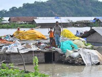 Villagers are taking shelter on the top of their partially submerged hut in a flood-affected area in Morigaon District of Assam, India, on J...