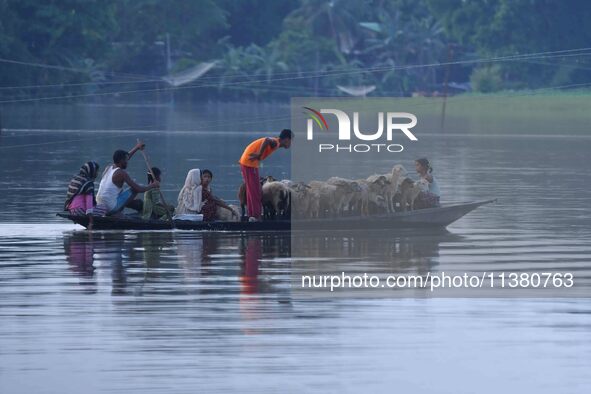 Indian villagers are traveling on a boat through a flooded village in Morigaon District of Assam, India, on July 3, 2024. 