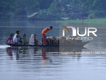 Indian villagers are traveling on a boat through a flooded village in Morigaon District of Assam, India, on July 3, 2024. (