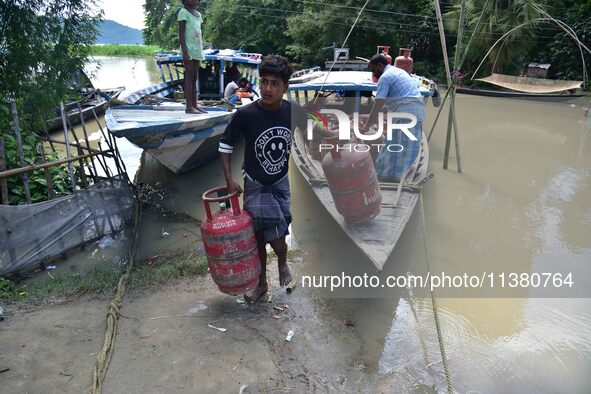 Villagers are shifting liquefied petroleum gas (LPG) cylinders to a safer place in Morigaon District of Assam, India, on July 3, 2024. 