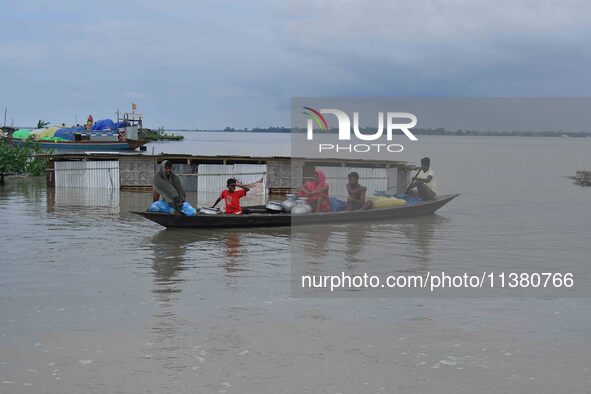 Indian villagers are traveling on a boat through a flooded village in Morigaon District of Assam, India, on July 3, 2024. 