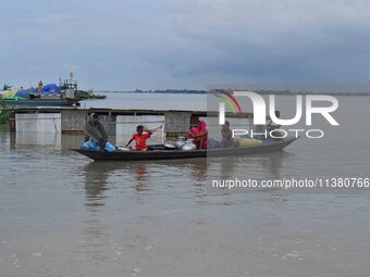 Indian villagers are traveling on a boat through a flooded village in Morigaon District of Assam, India, on July 3, 2024. (