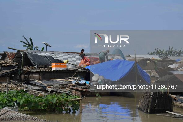 Villagers are taking shelter on the top of their partially submerged hut in a flood-affected area in Morigaon District of Assam, India, on J...