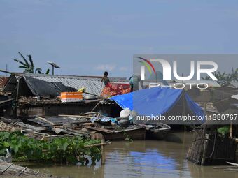 Villagers are taking shelter on the top of their partially submerged hut in a flood-affected area in Morigaon District of Assam, India, on J...