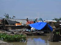 Villagers are taking shelter on the top of their partially submerged hut in a flood-affected area in Morigaon District of Assam, India, on J...