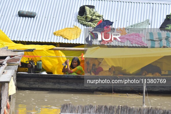 A woman is taking shelter on a boat as her house is submerging during floods in Morigaon district in Assam, India, on July 3, 2024. 