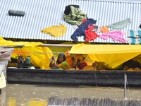 A woman is taking shelter on a boat as her house is submerging during floods in Morigaon district in Assam, India, on July 3, 2024. (