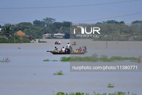 Indian villagers are traveling on a boat through a flooded village in Morigaon District of Assam, India, on July 3, 2024. 