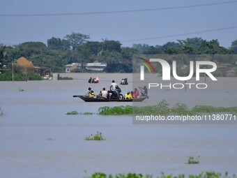 Indian villagers are traveling on a boat through a flooded village in Morigaon District of Assam, India, on July 3, 2024. (