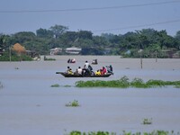 Indian villagers are traveling on a boat through a flooded village in Morigaon District of Assam, India, on July 3, 2024. (