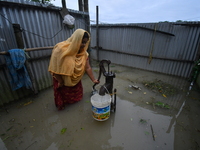 A woman is fetching water from a partially submerged hand pump in a flood-affected village in Nagaon district of Assam, India, on July 2, 20...