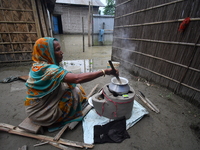 A woman is cooking inside her partially submerged house in the Bhurbandha village in Nagaon district of Assam, India, on July 2, 2024. (