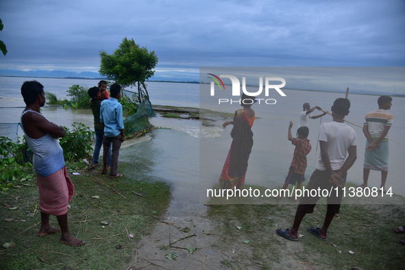 Flood-affected villagers are looking at a damaged road after heavy rains in Bhurbandha village in Nagaon district of Assam, India, on July 2...