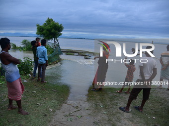 Flood-affected villagers are looking at a damaged road after heavy rains in Bhurbandha village in Nagaon district of Assam, India, on July 2...