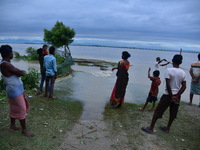 Flood-affected villagers are looking at a damaged road after heavy rains in Bhurbandha village in Nagaon district of Assam, India, on July 2...