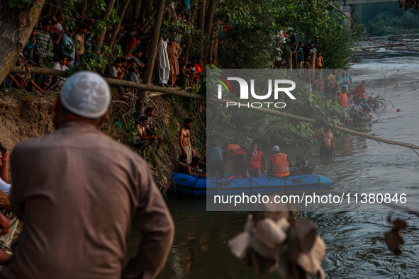 Villagers are watching as SDRF is launching an operation to trace the body of a young man who drowned in Nalla Puhroo while taking a bath on...