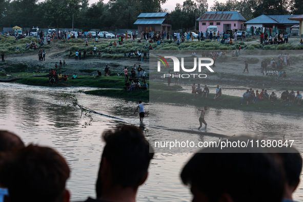 Villagers are watching as SDRF is launching an operation to trace the body of a young man who drowned in Nalla Puhroo while taking a bath on...