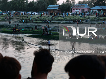 Villagers are watching as SDRF is launching an operation to trace the body of a young man who drowned in Nalla Puhroo while taking a bath on...