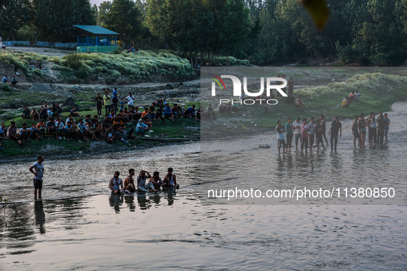 Villagers are watching as SDRF is launching an operation to trace the body of a young man who drowned in Nalla Puhroo while taking a bath on...