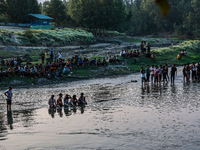 Villagers are watching as SDRF is launching an operation to trace the body of a young man who drowned in Nalla Puhroo while taking a bath on...